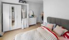 Luminoso dormitorio con armario blanco, cómoda, espejo redondo y acogedora cama doble en casa unifamiliar Felanitx