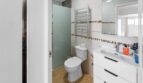 Baño luminoso con ducha, inodoro y lavamanos blanco en unidad residencial alquilada, Felanitx