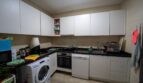 Cocina moderna con armarios blancos, encimera negra, horno empotrado, lavavajillas y lavadora en Felanitx
