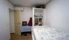 Dormitorio con cama individual, estantería, aire acondicionado y guitarra en casa unifamiliar alquilada en Felanitx.