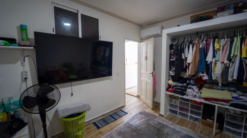 Dormitorio con TV montada en pared, armario abierto y aire acondicionado en casa de múltiples familias Felanitx