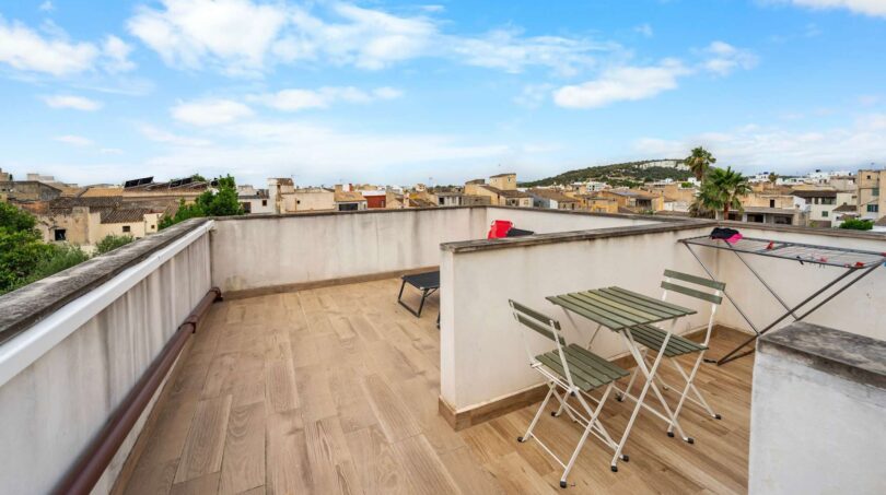Terraza de azotea con baldosas de madera, juego de bistró y vista a la ciudad en casa de múltiples familias alquilada en Felanitx
