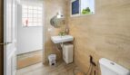 Baño luminoso con lavamanos, inodoro y azulejos beige en casa unifamiliar alquilada en Felanitx.