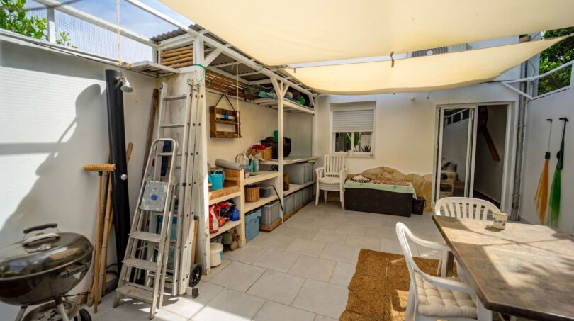 Terraza cubierta con vela solar, mesa de comedor, área lounge y estante de almacenamiento en casa unifamiliar, Felanitx