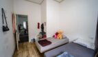 Dormitorio con dos camas individuales, suelo de madera y paso a la zona de estar en unidad alquilada en Felanitx.