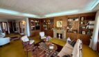 Elegant living room with wooden library, fireplace, retro floors and classic seating in Villa Porto Cristo.