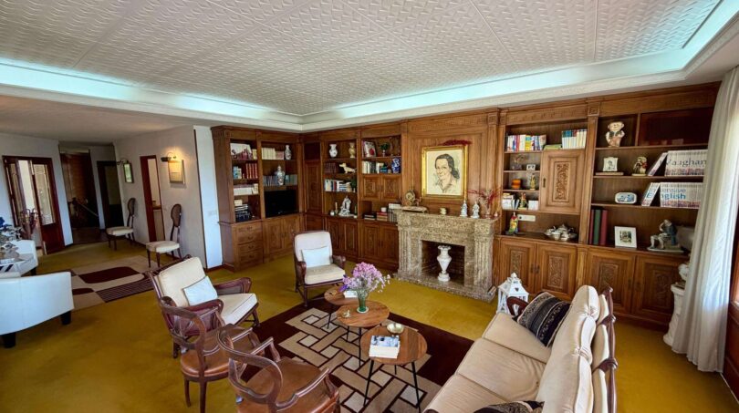 Elegant living room with wooden library, fireplace, retro floors and classic seating in Villa Porto Cristo.