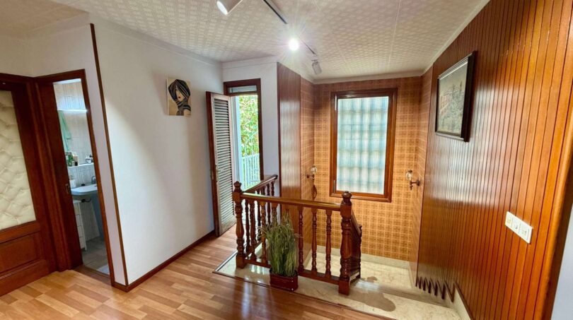 Upper staircase of the retro villa in Porto Cristo with wood panels, parquet floor and wooden railing.