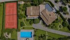 Aerial view of the villa in Porto Cristo with tennis court, pool, manicured garden and terracotta roof.