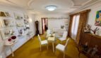 Elegant dining room of the retro villa in Porto Cristo with stucco ceiling, glass table and yellow carpet.