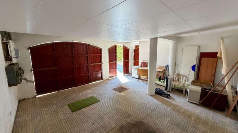 Spacious garage of the retro villa in Porto Cristo with three wooden doors and flat roof