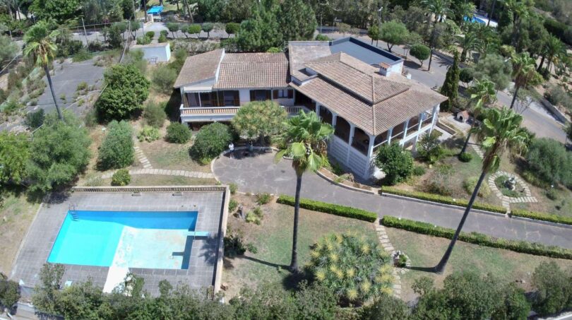 Aerial view of a Mediterranean villa in Porto Cristo with pool, palm garden and terracotta roof.