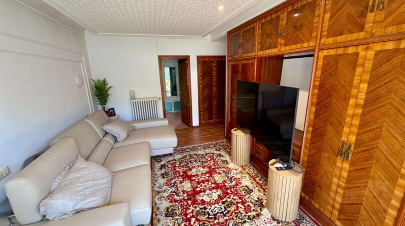 Living room of the retro villa in Porto Cristo with leather sofa, wooden cabinet and oriental rug