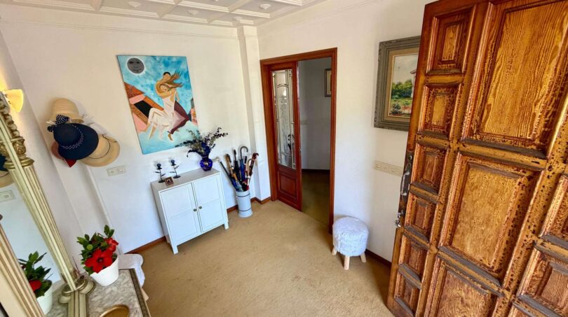 Elegant entrance area of the retro villa in Porto Cristo with coffered ceiling and rustic wooden door.