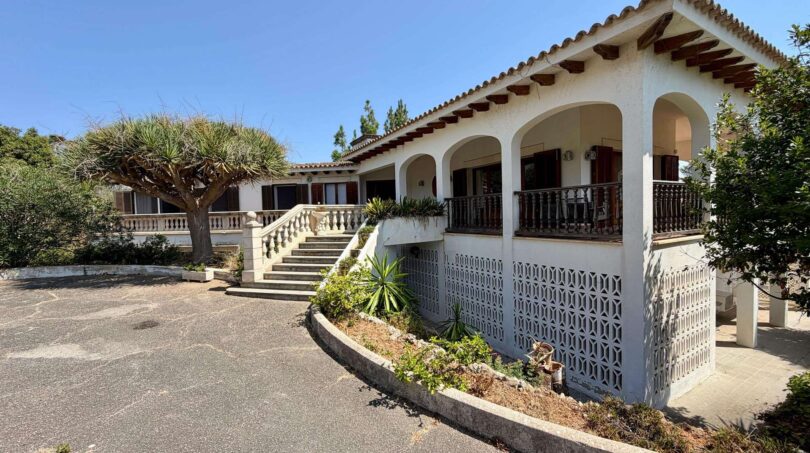 Outside view of the retro villa in Porto Cristo with white facade, arcades, balcony and large entrance area.