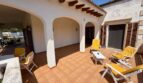Sunny terrace of the retro villa in Porto Cristo with sun loungers, round arches and terracotta tiles.