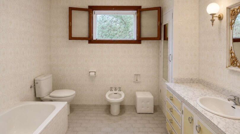 Bright retro bathroom with bathtub, bidet, toilet and marble sink in Villa Porto Cristo.