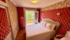 Elegant bedroom with red velvet upholstery, parquet floor and balcony with garden view in Retro-Villa Porto Cristo.