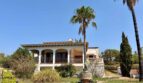 Outside view of a Mediterranean villa in Porto Cristo with arcade veranda, palms and well-maintained garden.