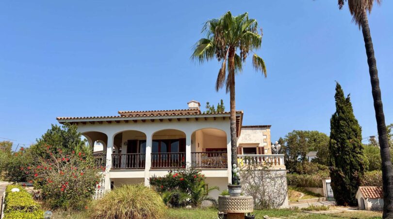 Outside view of a Mediterranean villa in Porto Cristo with arcade veranda, palms and well-maintained garden.