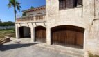 Stone-clad garage with three wooden doors and balcony of the retro villa in Porto Cristo
