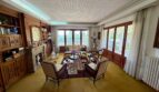 Elegant living room of the retro villa in Porto Cristo with fireplace, wood paneling and balcony access.