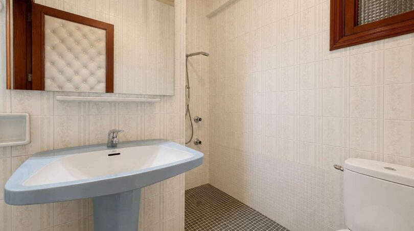 Bright bathroom of the retro villa in Porto Cristo with pedestal sink, shower and mosaic tile floor.