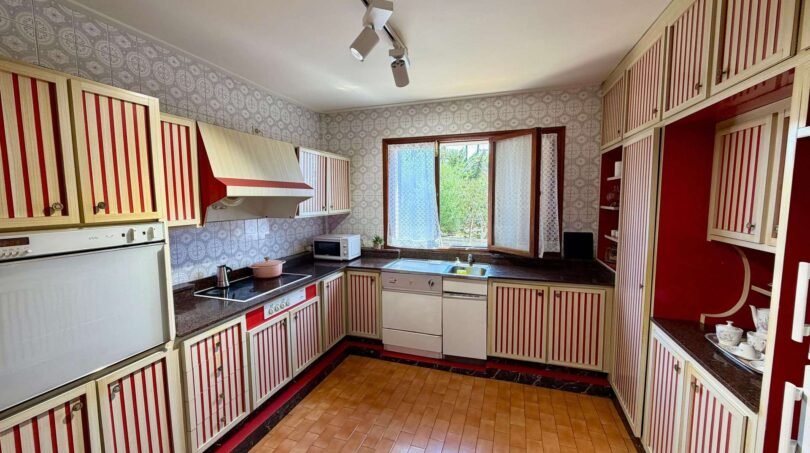 Retro kitchen with red and white striped cabinets, marble counter and terracotta floor in Villa Porto Cristo