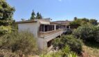 Outside view of the retro villa in Porto Cristo with balcony, white facade and lush Mediterranean garden.
