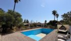 Large outdoor pool of the retro villa in Porto Cristo with sun loungers, canopy bed and palms