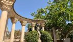 Semi-circular columned colonnade with sculpture and trees in the garden of the retro villa in Porto Cristo.