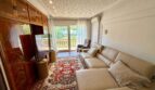 Living room of the retro villa in Porto Cristo with leather sofa, wooden cabinet and balcony access.