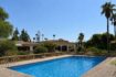 Large outdoor pool of the retro villa in Porto Cristo with Mediterranean balustrade and palm garden