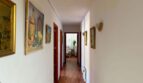 Long hallway of the retro villa in Porto Cristo with parquet floor, red doors and paintings on the walls.