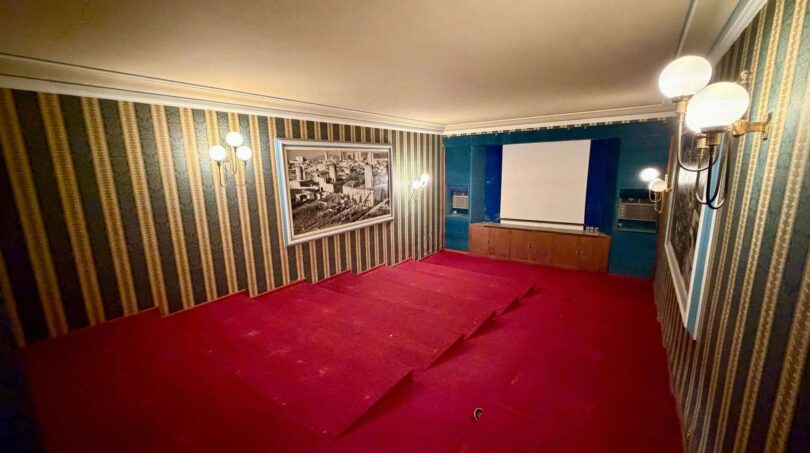 Cinema room with red carpet, striped wallpaper, wall lights and projection screen in Retro-Villa Porto Cristo.