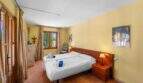 Helles Schlafzimmer der Windmühlen-Finca in Felanitx mit Doppelbett, Terrakottaboden und gelben Wänden.