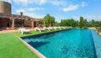 Großer Infinity-Pool mit weißen Liegestühlen, Pergola und Steinhaus der Windmühlen-Finca in Felanitx
