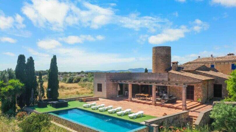 Außenansicht der Finca mit Pool, Liegestühlen, Pergola und historischem Windmühlenturm in Felanitx