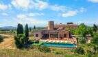Luftaufnahme einer Finca mit Windmühlenturm, Pool und Terrasse in Felanitx, umgeben von Weinreben.
