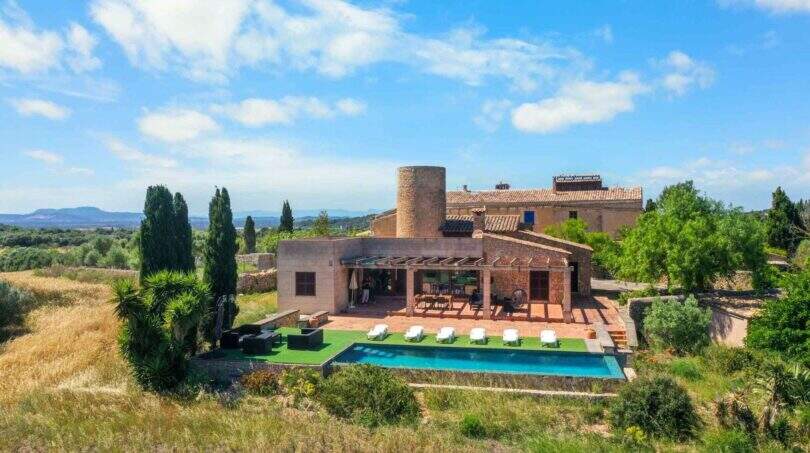 Luftaufnahme einer Finca mit Windmühlenturm, Pool und Terrasse in Felanitx, umgeben von Weinreben.