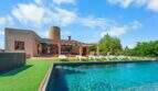 Außenbereich der Finca in Felanitx mit großem Pool, Liegestühlen, Pergola und historischem Windmühlenturm.