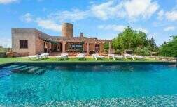 Outdoor pool with lounge chairs and historic windmill of a finca with ETV license in Felanitx, Mallorca