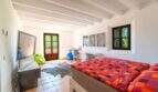 Spacious bedroom of the Felanitx finca with wooden beam ceiling, double bed and basketball wall decoration.