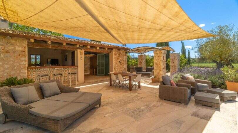 Sunny terrace of the Felanitx finca with sail shade, lounge, outdoor kitchen and stone arches