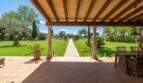 Covered terrace with columns, garden view and stone path of the finca in Felanitx