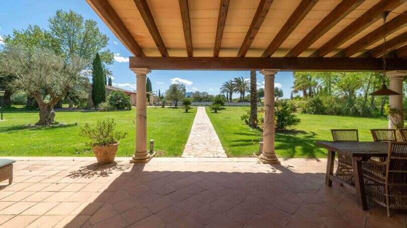 Covered terrace with columns, garden view and stone path of the finca in Felanitx