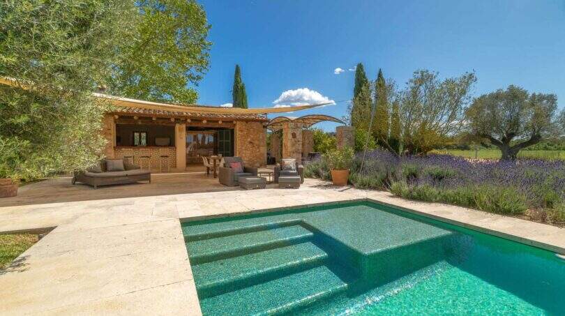 Felanitx finca: Pool with jacuzzi, natural stone terrace, lounge area and lavender garden under blue sky