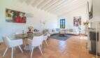 Bright living-dining area of the Felanitx finca with terracotta floor, white wooden beams and modern furnishings.