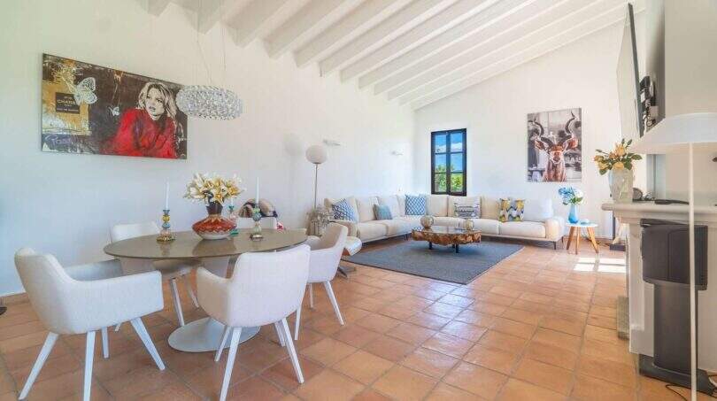 Bright living-dining area of the Felanitx finca with terracotta floor, white wooden beams and modern furnishings.