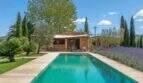 Felanitx finca: Long pool with natural stone house, lavender, cypress trees and olive trees under blue sky